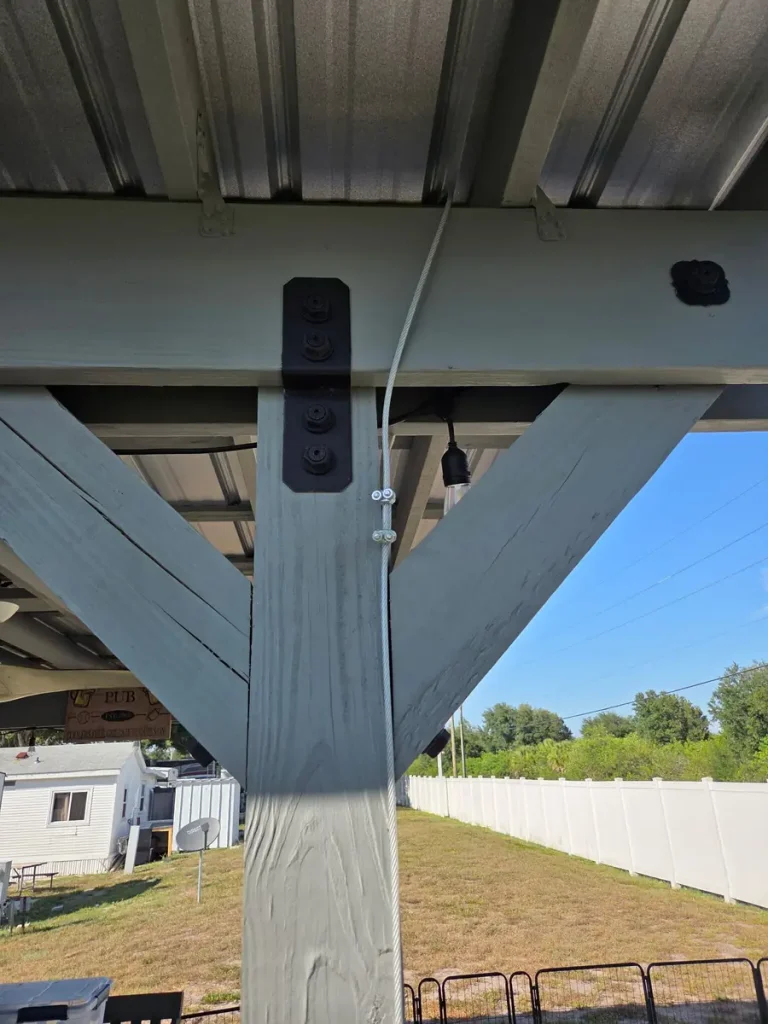 Carport post strapped to a ground anchor